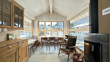 Ferienwohnung in Kandersteg - Livingroom mit Tisch, beheizter Sitzbank Kaminofen