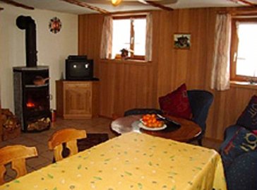 Ferienhaus in Riederalp - Wohnraum mit Esstisch, Schwedenofen und TV