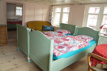 Ferienwohnung in Appenzell - Betten, Tisch, Sofa, Kommode, Türe zum Nebenzimme